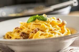 Italian food pasta tagliatelle carbonara with pancetta parmesan egg yolk and basil leaves photo