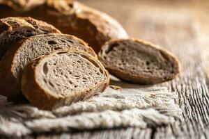 Closeup of fresh slices of organic homemade bread loafs on a rustic cloth and wooden table photo