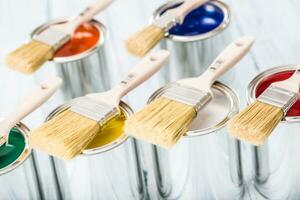 Close-up brushes lying on multicolored paint cans. photo