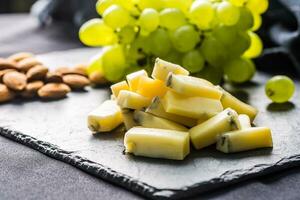 Cheese pieces juicy grapes and walnuts on slate board photo