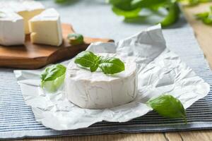 queso Camembert o queso Brie queso con albahaca hojas en mesa foto