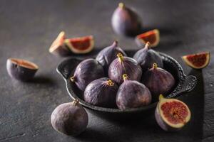 A few figs in a black bowl on an dark concrete table photo