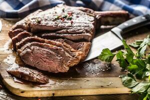 recién A la parrilla tomahawk filete en pizarra plato con sal pimienta Romero y perejil hierbas. rebanado piezas de jugoso carne de vaca filete foto