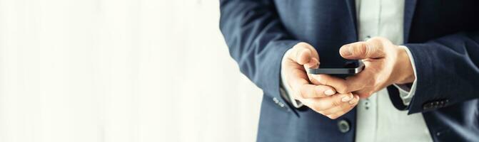 Businessman in blue suit holding a black smartphone in hands and chatting with collegues photo