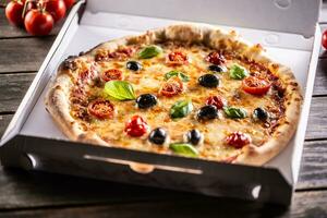 Pizza in a cardboard box on table ready to customer. photo