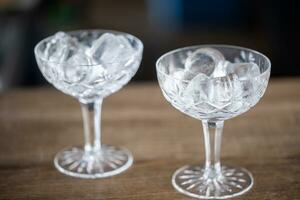 Two ornamental cocktail glasses being cooled with cubes of ice in them photo