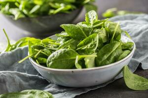 Fresh baby spinach in bowl on dark kitchen table photo