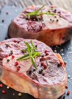 Two pieces raw beef shank on slate board and wooden table. photo