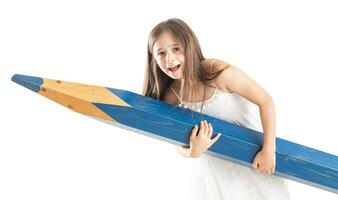 un linda pequeño niña con genial esfuerzo sostiene un enorme azul lápiz en su manos - aislado en blanco foto