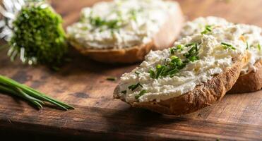 Close up of a thick spread of sheep cheese on slices of bread with finely chopped chives on top photo