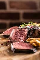 Grilled beef steak with potato fries on wooden board photo