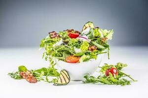 Fresh vegetable salad with fried bacon tomatoes olives arugula zucchini tzatziki dressing and olive oil photo