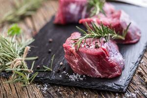 Raw beef meat. Raw beef tenderloin steak on a cutting board with rosemary pepper salt in other positions. photo