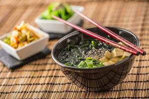 tradicional japonés sopa miso con tofu algas marinas palillos y joven cebolla foto