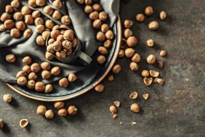 Top view of hazelnuts and their cracked shells on a rustic dark metallic background, in a metallic cup and on a tray photo