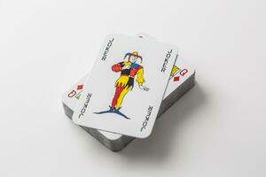 Joker card on top of pile of playing cards on an isolated white background photo