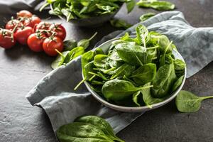 Fresh baby spinach in bowl on dark kitchen table photo