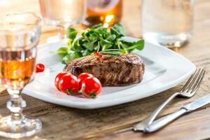 Beef Steak. Juicy beef steak. Gourmet steak with vegetables and glass of rose wine on wooden table photo