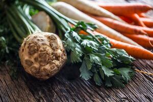 Vegetable. Fresh root vegetable celery carrot and parsnip on rustic oak table photo