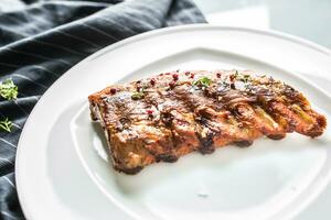 Grilled barbecue pork ribs in a white plate as menu in pub. photo