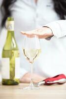 hembra participación un mano encima el vaso de blanco vino con botella y vino abrelatas siguiente a eso foto