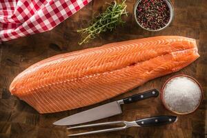 Whole raw salmon fillet on a wooden butchers board photo