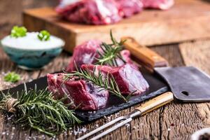 Raw beef meat. Raw beef tenderloin steak on a cutting board with rosemary pepper salt in other positions. photo