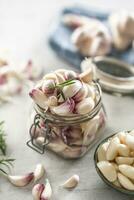 TJar full of garlic cloves, garlic bulbs on a cloth in the background photo