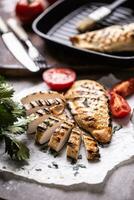 Chicken breast slices grilled on paper with celery herbs and tomatoes photo