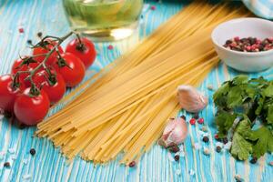 Pasta and cooking ingredients on blue wooden background. photo