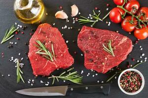 Fresh raw beef steak with spice on black background photo