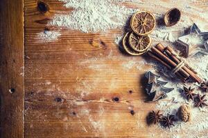 Top of view bakery table full of christmas aromatic ingredients star anise cinnamon dried orange flour cookery book and cookie cutters photo