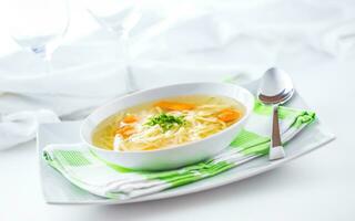 Lunch setting table with chicken or beef soup with noodles carrot and herbs photo