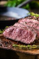 Beef steak. Juicy medium Rib Eye steak slices on wooden board with fork and knife herbs spices and salt photo