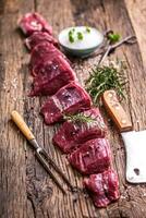 Raw beef meat. Raw beef tenderloin steak on a cutting board with rosemary pepper salt in other positions. photo