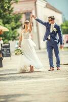 un novio bailando con su novia en el pueblo después un boda. todavía vistiendo hermosa batas y participación un ramo de flores hecho de blanco flores foto