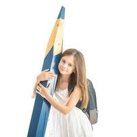 Cute little girl with a school bag holds a huge blue pencil in her hands - Isolated on white photo