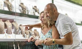 de edad mediana Pareja en amor mirando a oro y plata anillos o cadenas en joyería Tienda foto