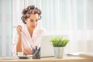 Beautiful girl with curlers in her hair reads from her notebook photo