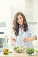 joven mujer preparando vegetal ensalada en su cocina. sano estilo de vida concepto hermosa mujer con mezclado vegetal foto