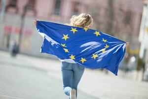 atractivo contento joven niña con el bandera de el europeo Unión foto