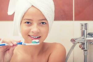 Adolescente niña en el baño con cepillo de dientes. dental higiene foto