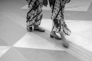 dos mujer vistiendo estampado vestidos caminando en un loseta piso foto