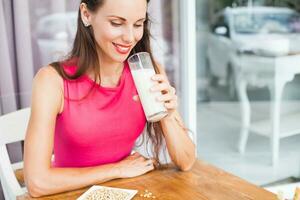 un mujer es sonriente mientras participación un vaso de Leche foto