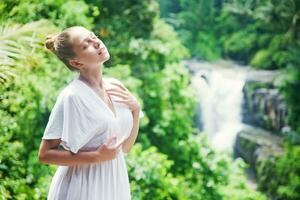 beautiful woman in white dress standing in front of waterfall photo