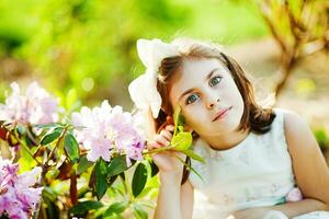 a young girl is sitting in the grass with flowers photo