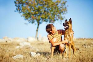 a boy is hugging a dog in a field photo