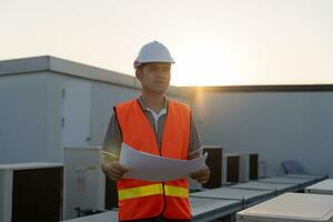 Asian maintenance engineer works on the roof of factory. contractor inspect compressor system and plans installation of air condition systems in construction. Checklist, inspector, control photo