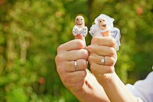 a man and woman holding finger puppets with wedding rings photo