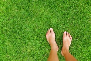 a person's bare feet on a green grassy field photo